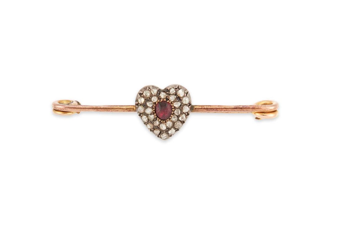 A RUBY AND DIAMOND HEART BAR BROOCH: an oval-cut ruby within a rose-cut diamond-set heart, stamped '9CT'. 4.5cm long, 3 grams Light abrasion to the ruby