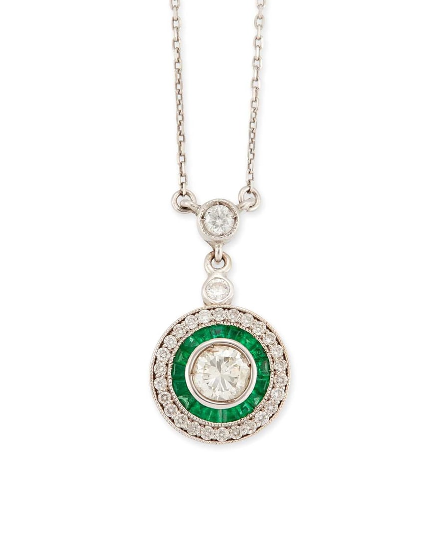 AN ART DECO STYLE EMERALD AND DIAMOND PENDANT ON CHAIN: a round brilliant-cut diamond within a border of calibre-cut emeralds and round diamonds, to a diamond-set bail and fine chain, stamped '750'. Total estimated diamond weight 0.60 carat, pendant 2cm
