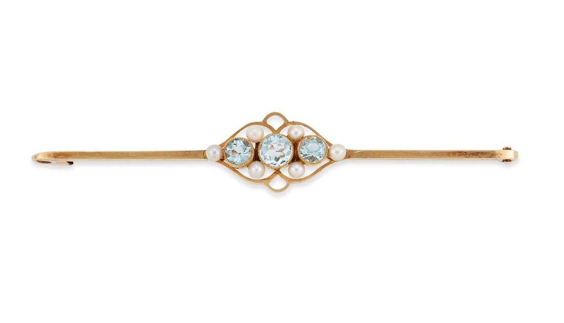AN AQUAMARINE AND SEED PEARL BAR BROOCH: three graduated round-cut aquamarine spaced by seed pearls, to a flat-sided bar, stamped '15CT'. 6.5cm long, 3.6 grams Good condition