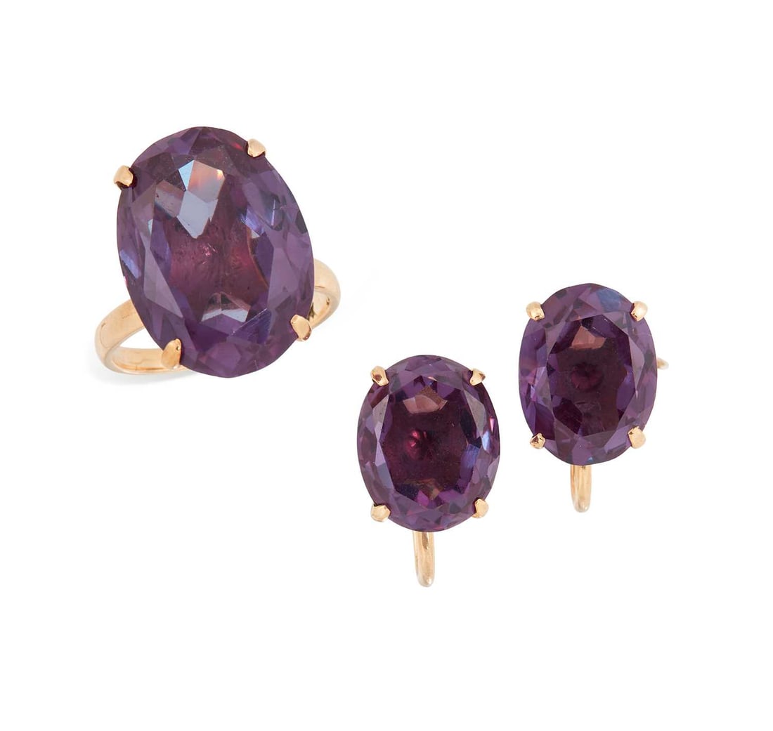 A SYNTHETIC COLOUR CHANGE SAPPHIRE RING AND PAIR OF EARRINGS: of oval-cut synthetic colour change sapphires in claw settings, the earrings with screw fittings, stamped '14K'. (2) Ring size J, earrings 1.2cm long, 10.8 grams gross Good condition