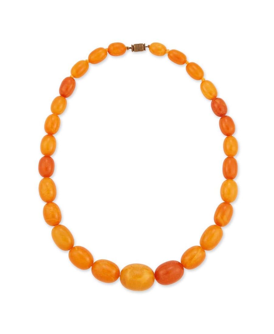 A BUTTERSCOTCH AMBER BEAD NECKLACE: formed of twenty-seven graduated oval amber beads, to a barrel clasp. 57cm long, 71 grams Good condition. Largest bead 2.5cm x 1.7cm approx