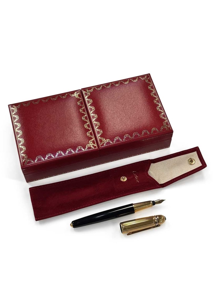 A MUST DE CARTIER PASHA DE CARTIER FOUNTAIN PEN: black lacquer barrel, the reeded gold plated cap with a trilogy ring band, with a Cartier nib stamped '18K' '750', within the original box with the International Guarantee Certificate. 14cm long