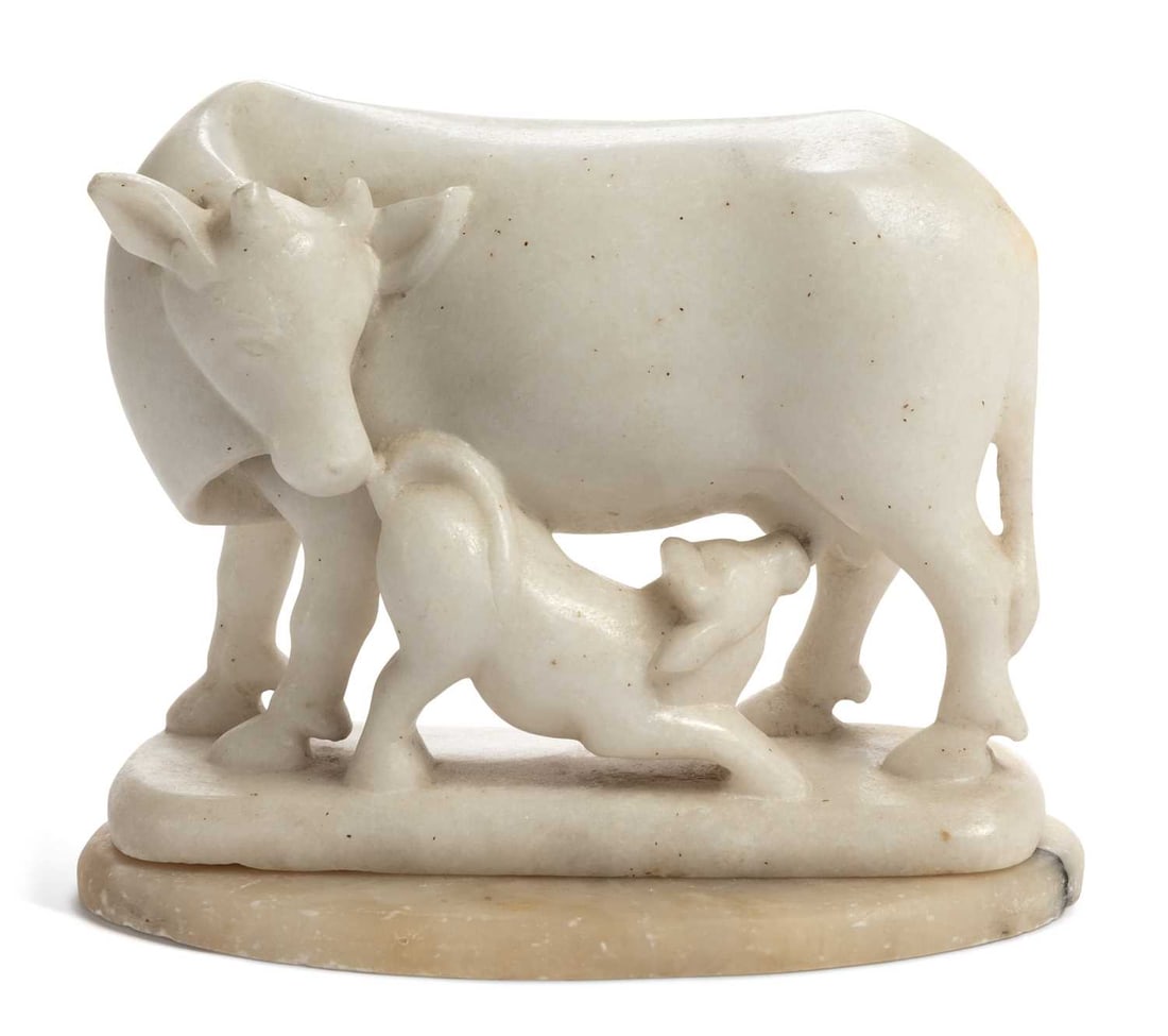 AN ALABASTER COW AND CALF GROUP 19TH CENTURY: carved as a calf suckling from her mother, set upon a separate oval base. 17.5cm long