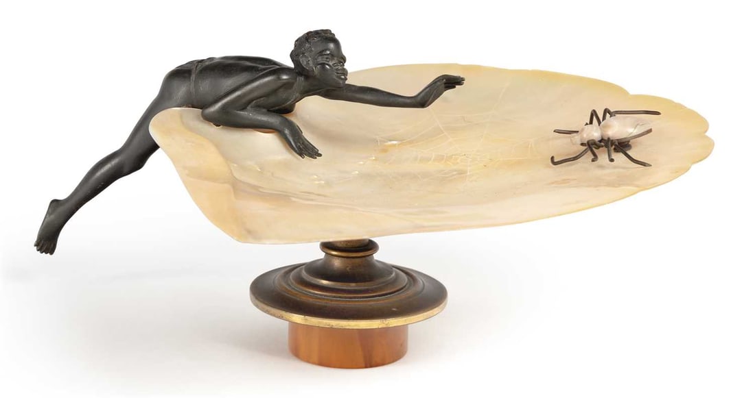 AN AUSTRIAN BRONZE AND MOTHER-OF-PEARL DISH CIRCA 1890: amusingly modelled as a figure reaching towards a spider climbing through its web, carved into a large mother-of-pearl dish, set upon a gilt-bronze and amber pedestal. 22cm wide Small nibbles to the r