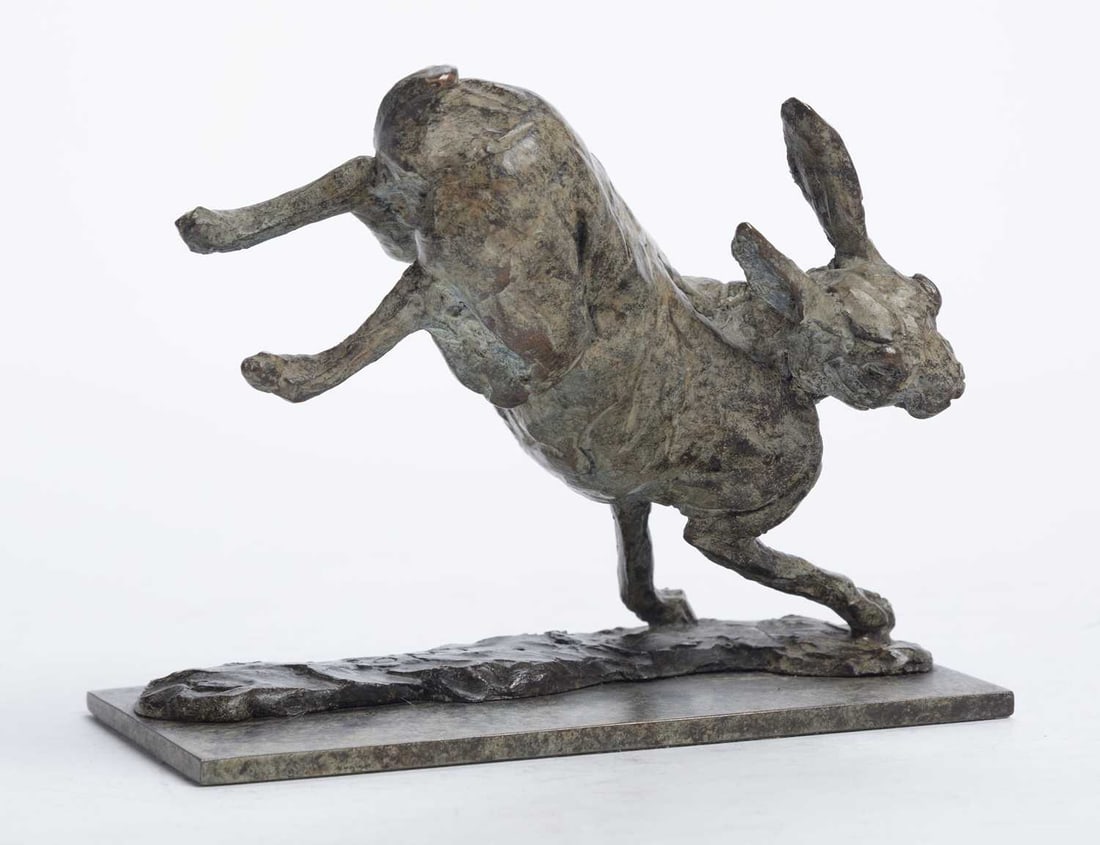 A CAROLINE WALLACE BRONZE MODEL OF A HARE: signed with initials and dated 03, numbered 2/9, modelled running with the ears laid back, on a rectangular base cast in relief. 12cm high