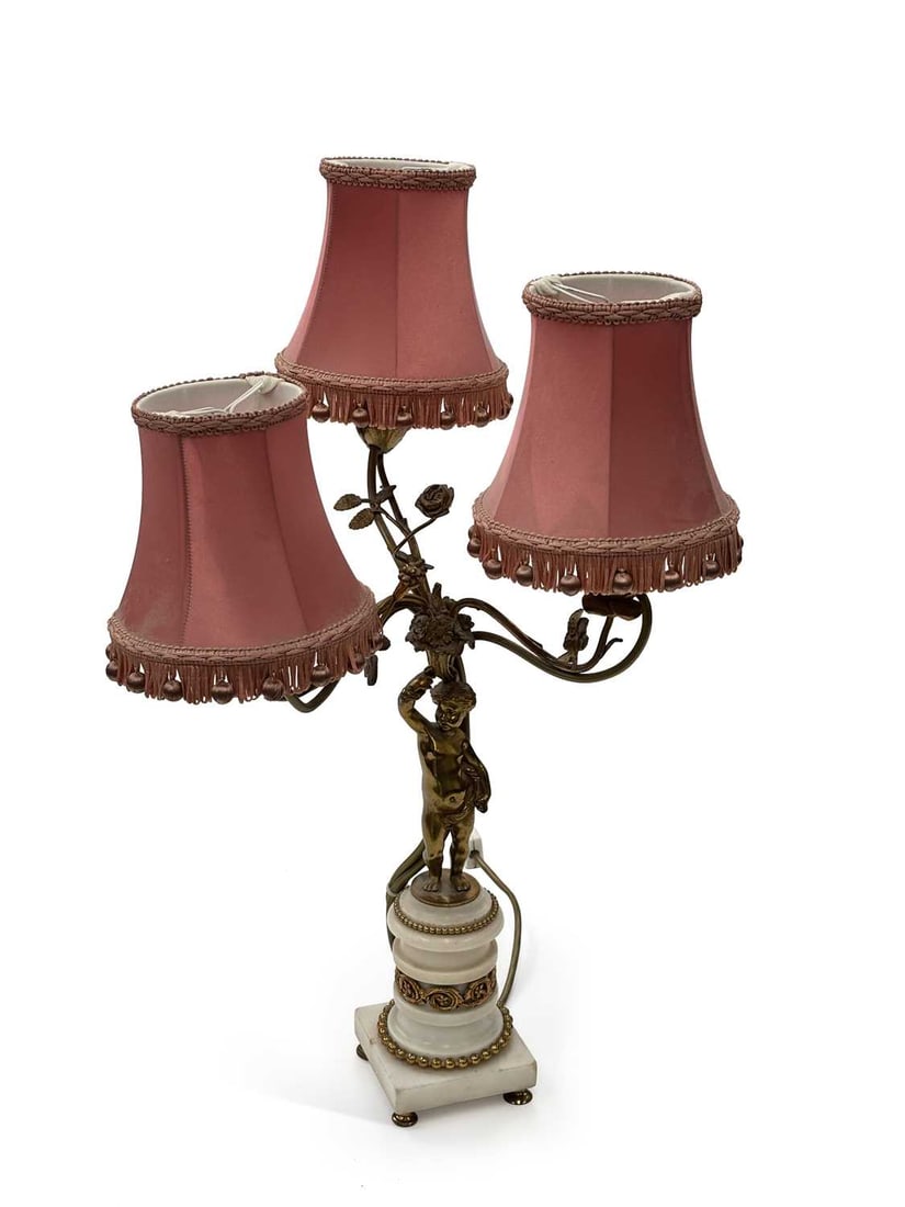 A FRENCH GILT METAL AND WHITE MARBLE FIGURAL TABLE LAMP 19TH CENTURY: modelled as a putto with a raised arm supporting three naturalistic scrolling branches cast with roses, foliage and a bird, each terminating in a flowerhead nozzle, on a stepped and turned white