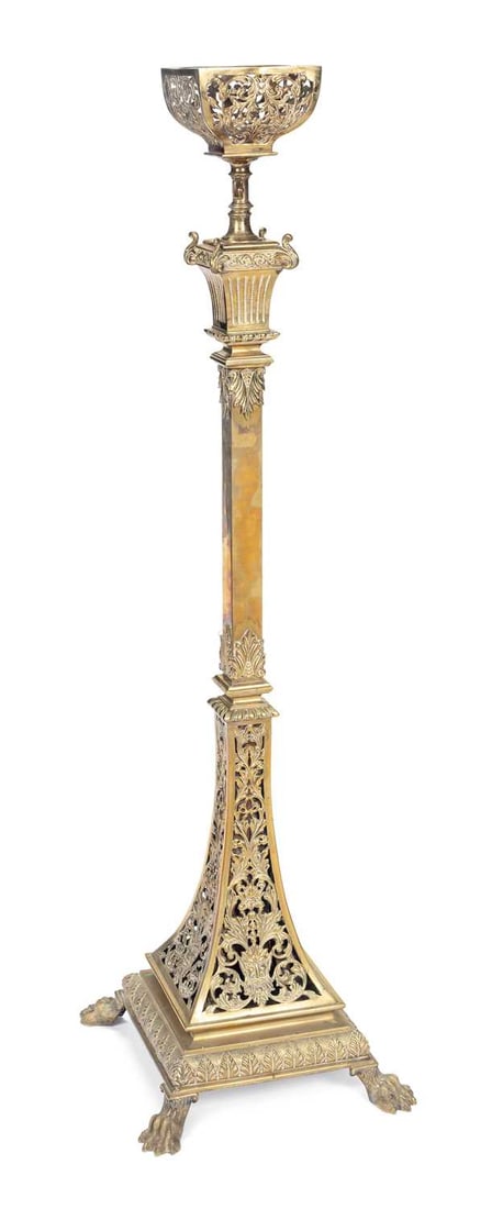 A LATE VICTORIAN BRASS STANDARD LAMP: the pierced foliate scroll font holder on a knopped stem above a fluted and acanthus capital, the square tapering column raised on a pierced foliate scroll base within stiff leaf borders, on lion paw