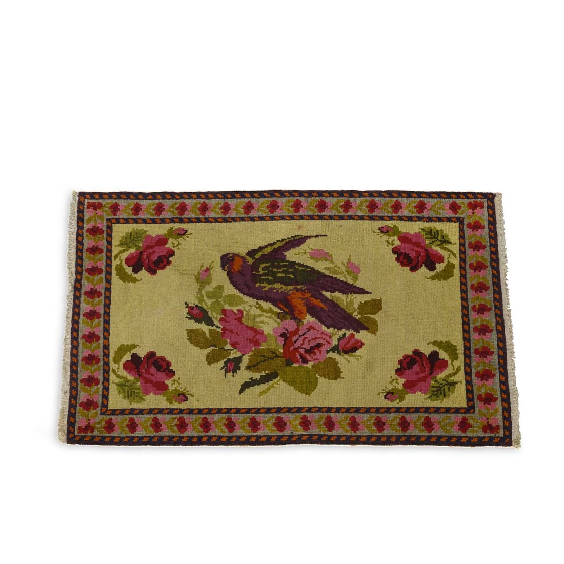 A SMALL WOOL RUG IN THE CHINESE TASTE: the pale field decorated with a bird perched amid flowering roses, within a rose-pattern border and narrow guard stripes, with fringed ends. 100cm by 64cm