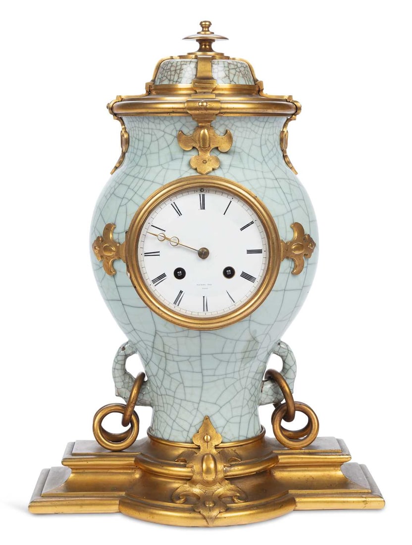 A FRENCH ORMOLU-MOUNTED CHINESE CRACKLE GLAZED PORCELAIN MANTEL CLOCK: by Raingo Freres, Paris, third quarter 19th Century, the celadon crackle glazed baluster vase applied with palmette mounts and ring handles, surmounted by an urn finial and raised on a stepped shaped 
