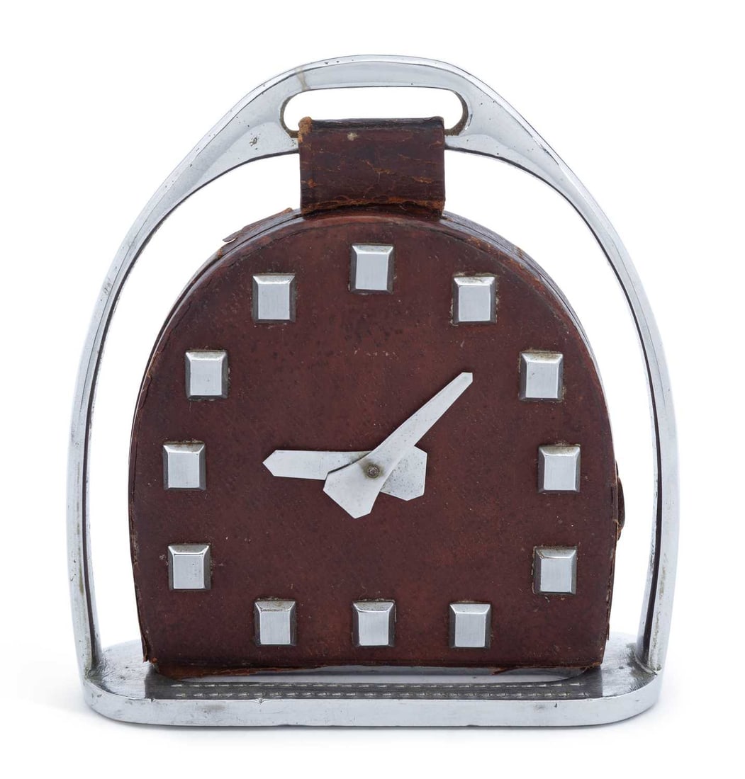 AN ART DECO STYLE HORSE STIRRUP TABLE CLOCK: the arch shaped dial unsigned, in chrome steel and leather. 12.5cm high