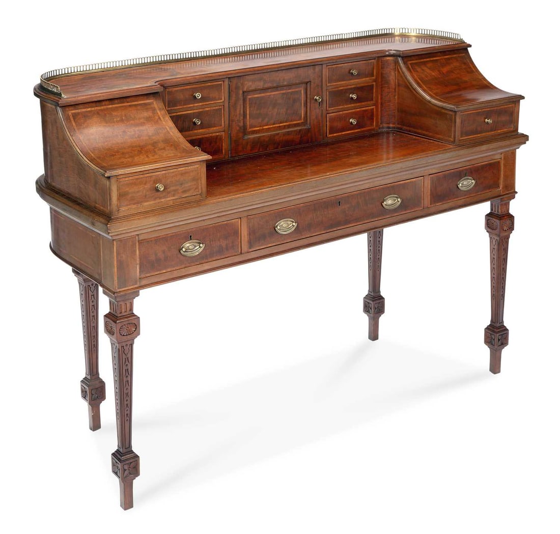 A MAHOGANY CARLTON HOUSE DESK EARLY 20TH CENTURY: in the George III taste, the superstructure with a pierced brass three quarter gallery above an arrangement of small drawers and a central panelled cupboard between curved end sections fitted with