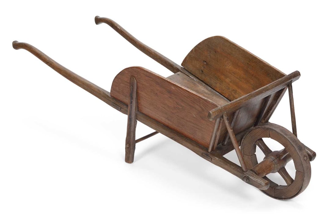 A 19TH CENTURY OAK CHILD'S WHEELBARROW: of planked construction with shaped sides, on a mortised frame with swept handles and splayed struts, the solid wheel with five spokes and turned hub. 96cm long