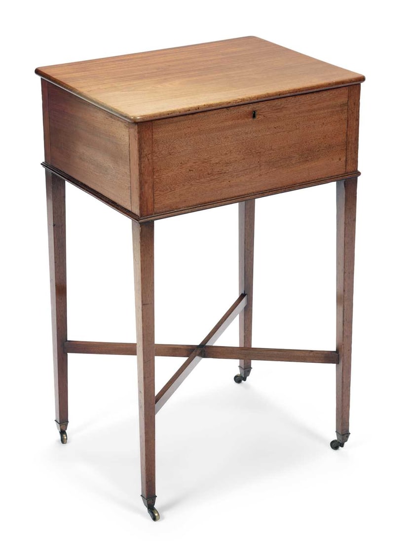 A 19TH CENTURY MAHOGANY WORK TABLE: the hinged rectangular top enclosing a well, with a side drawer fitted with divisions for sewing implements, on square tapering legs joined by an X stretcher, on brass castors. 76cm high, 48.5cm