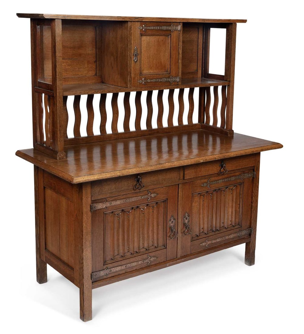 AN ARTS AND CRAFTS OAK SIDEBOARD: the superstructure with a cupboard door flanked by recesses, the base with a moulded rectangular top above a pair of drawers over a pair of linen-fold carved cupboard doors, fitted with copper hinges 