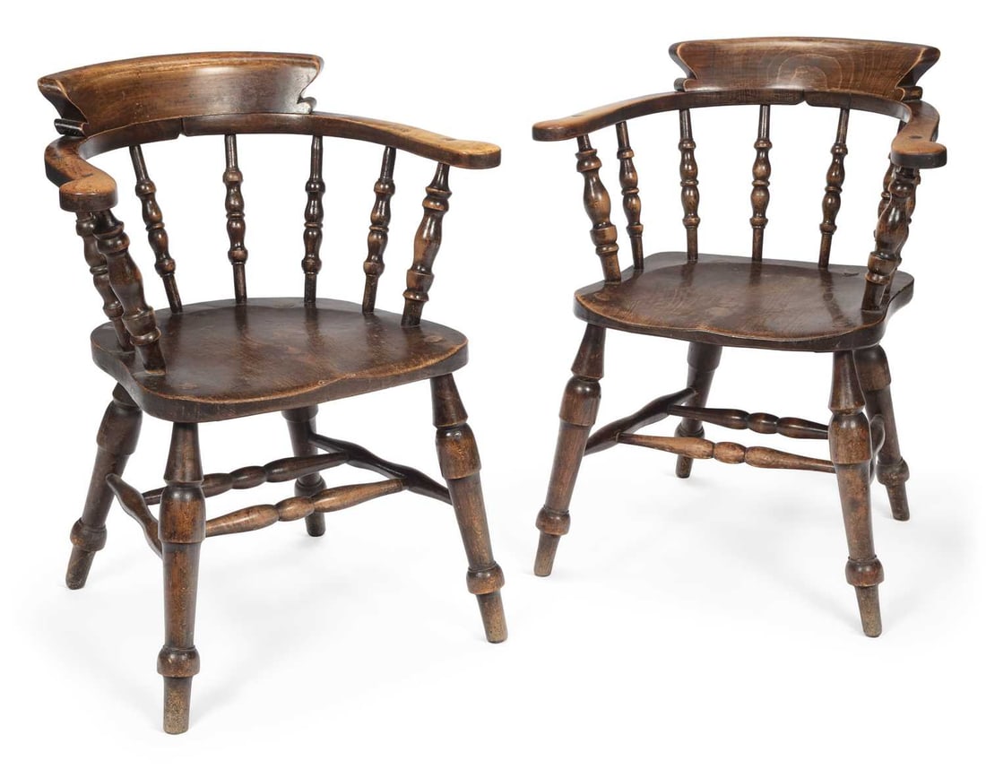TWO ELM AND BEECH SMOKER'S BOW ARMCHAIRS 19TH CENTURY: each with a shaped crest rail above turned spindles continuing to form the arms, the saddle seat raised on turned legs joined by turned stretchers. (2) Height of backs 80cm
