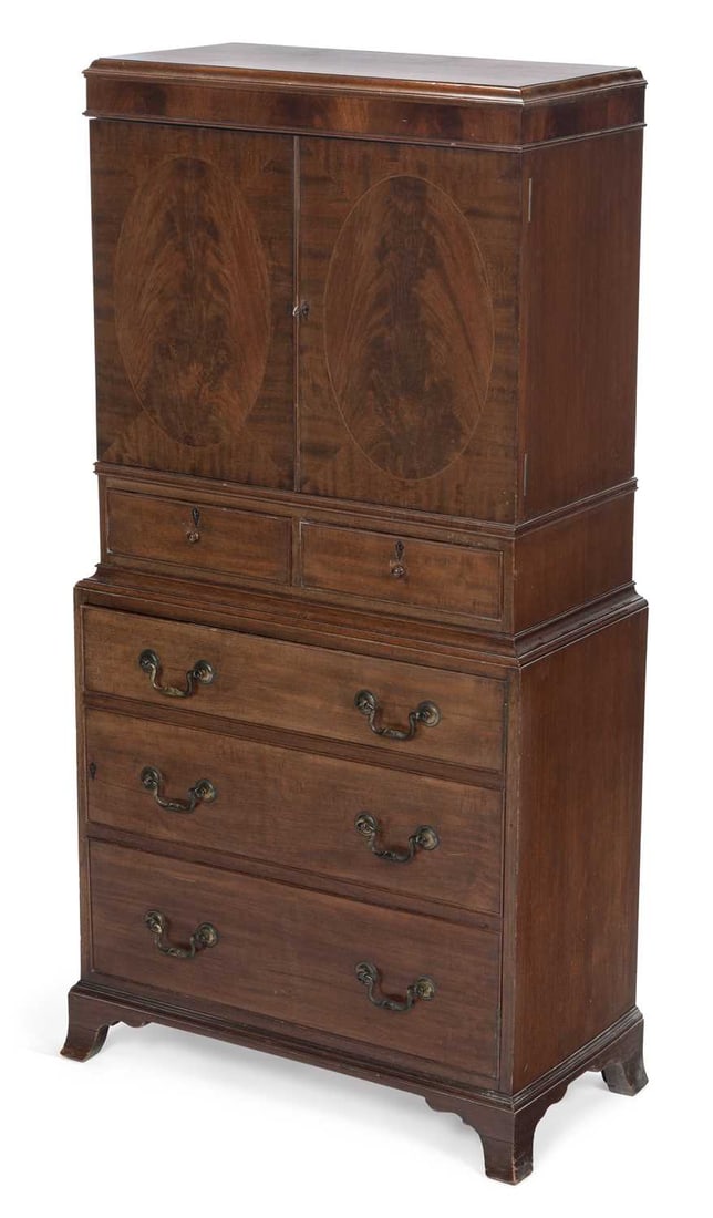 A GEORGE III STYLE MAHOGANY CABINET ON CHEST WARING & GILLOW: the moulded cornice above a pair of doors, each with an oval flame mahogany panel within boxwood stringing, enclosing an oak-lined interior with a shelf, above two short drawers and a cupboard door wi
