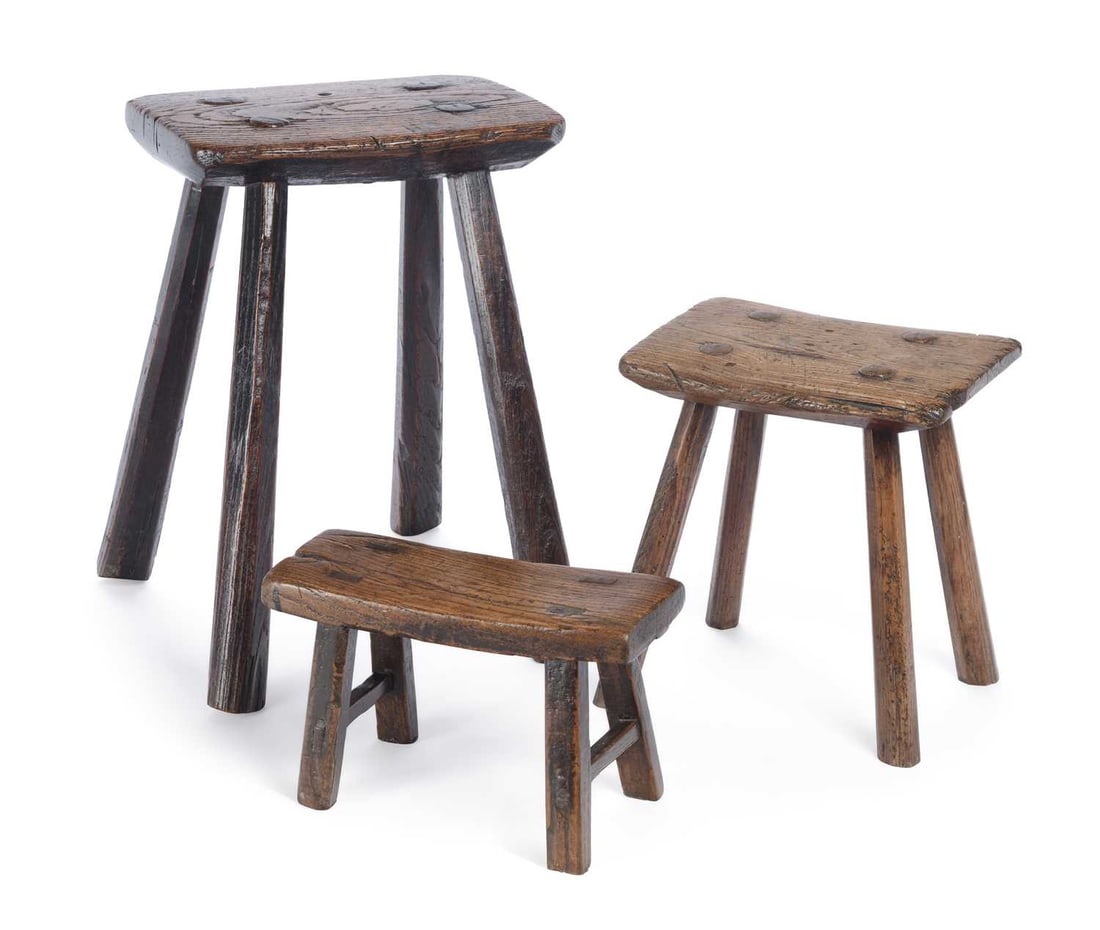 THREE ELM AND ASH COUNTRY STOOLS 18TH/ 19TH CENTURY: each with a shaped plank seat raised on splayed legs with wedged tenons, comprising two four-legged stools and a low bench stool. (3) Tallest 42.5cm high