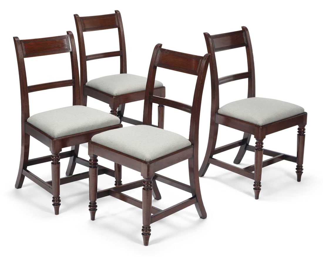 A SET OF FOUR 19TH CENTURY MAHOGANY DINING CHAIRS: in the Regency taste, each with a panelled tablet top rail and cross rail between reeded uprights, above a drop in upholstered seat, on ring turned tapering front legs joined by stretchers, the rear