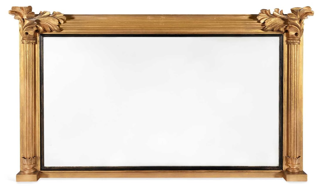 A REGENCY GILTWOOD OVERMANTEL MIRROR: the rectangular plate within an ebonised reeded slip, flanked by half round reeded columns with carved acanthus capitals and moulded blocks, beneath a stepped moulded cornice. 85cm high, 144cm wide
