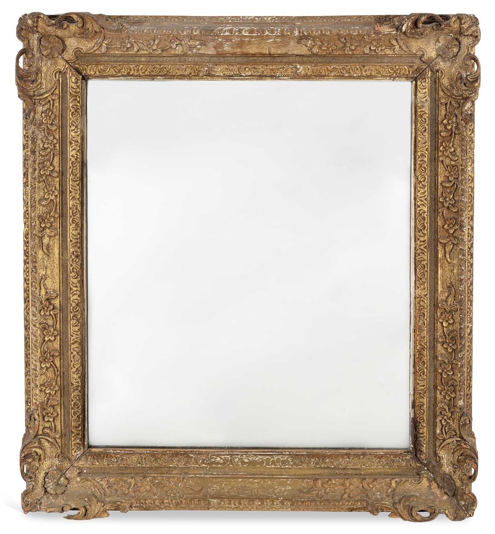 A CARVED GILTWOOD AND GESSO MIRROR: in the Louis XIV taste, the rectangular plate within a moulded frame carved with a band of flowerheads and trailing foliage, the angles with pierced scroll cartouches, the reverse with a panelled back