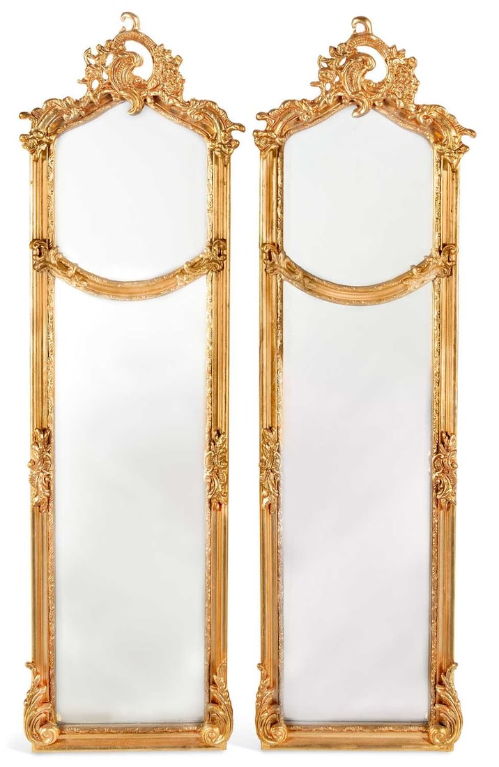 A PAIR OF GILT COMPOSITION PIER MIRRORS: in the Louis XV taste, each surmounted by a pierced rocaille and floral cresting above a shaped bevelled plate, over a long rectangular bevelled plate, the moulded frame applied with foliate cartouche