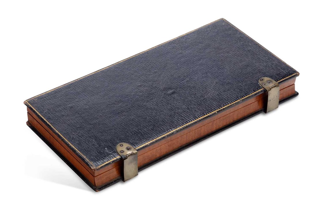 A VICTORIAN FOLDING TRAVELLING GAMES BOARD: the leather-covered case with gilt line borders and brass clips, opening on brass hinges to a chessboard veneered in ebony and satinwood within boxwood stringing, together with a quantity of turned bo