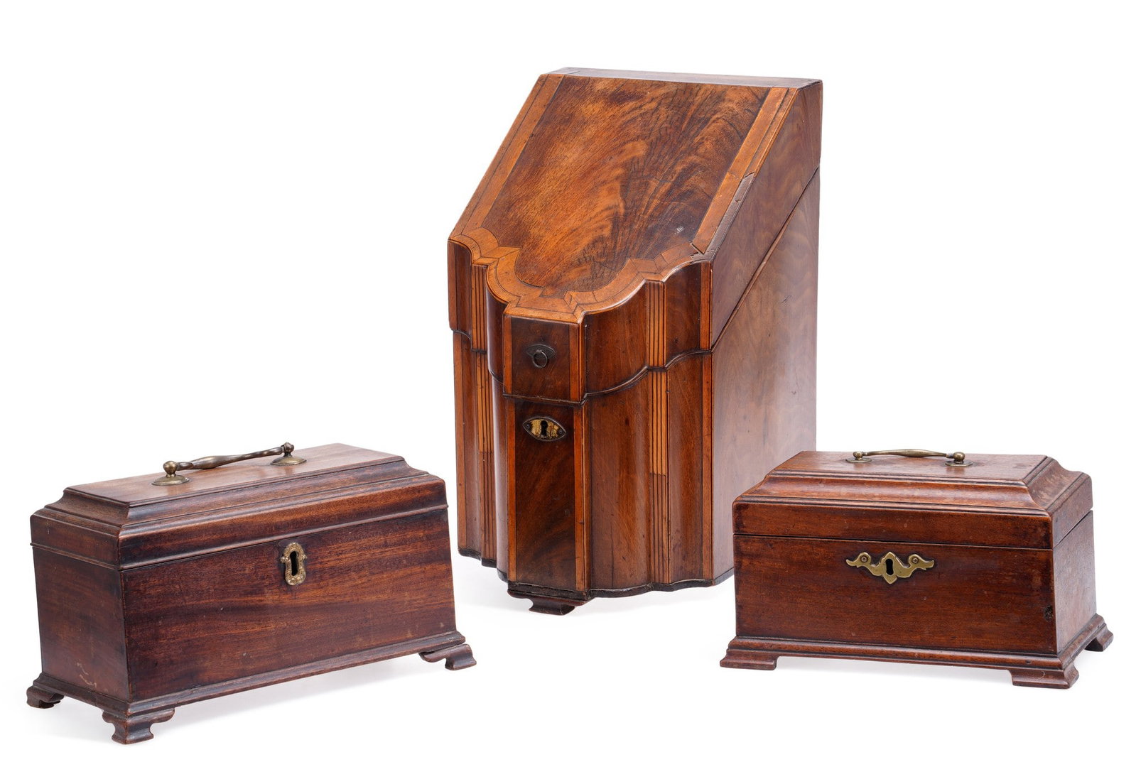 A GEORGE III MAHOGANY KNIFE BOX AND TWO TEA CADDIES: the knife box of serpentine form, crossbanded and strung throughout with reeded canted angles, the sloping hinged cover enclosing a fitted interior of five divisions, the interior of the cover inlaid 
