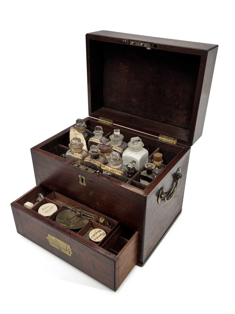 A GEORGE III MAHOGANY APOTHECARY'S BOX: of rectangular form with brass side carrying handles and shaped escutcheons, the hinged cover enclosing a compartmented interior with glass bottles and stoppers, several retaining printed labels