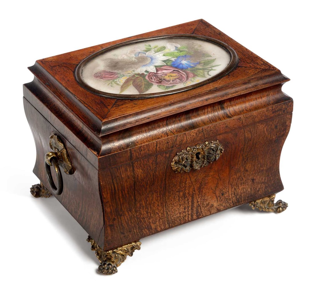 A 19TH CENTURY ROSEWOOD SARCOPHAGUS-FORM TEA CADDY: the hinged cover inset with a glazed floral painted panel, enclosing a fitted interior with a cut-glass mixing bowl and lidded caddy, with gilt-brass ring handles, escutcheon and paw feet. 16.5cm high