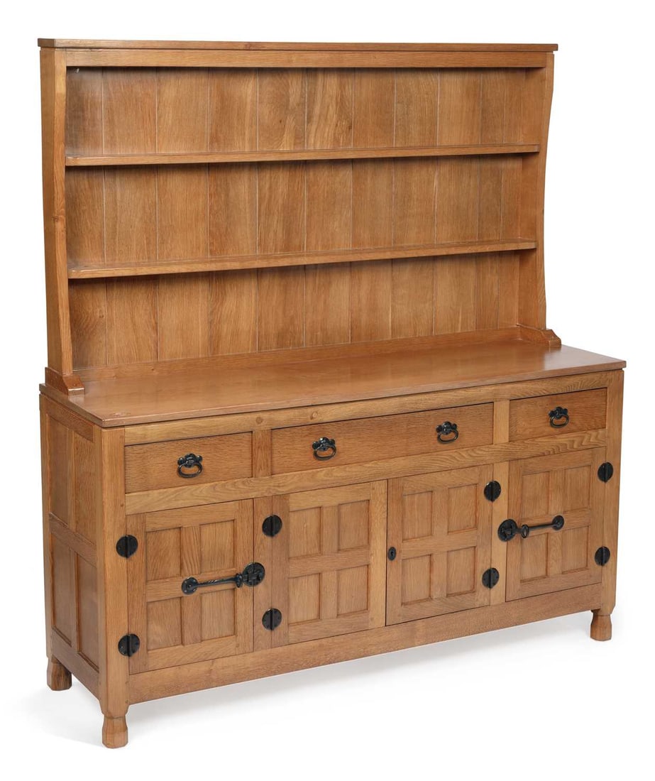 DEREK SLATER A FISHMAN OAK DRESSER: the raised plate rack with two shelves within a panelled back and shaped sides beneath a moulded cornice, the base with a rectangular top carved to one corner with the fish signature, above three frie