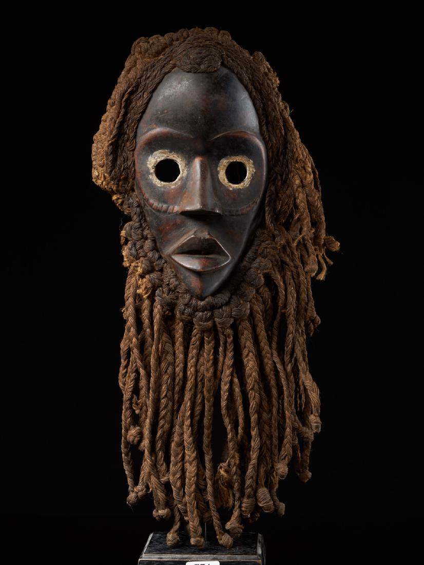 Dan mask, Ivory Coast: A dark coloured Dan Face Mask. It has been adorned with hair and a large beard made from rope/vegetal fibres. The mask has a stern design with large round eyes. Dimensions: approx 25 x 17 x 10 cm with