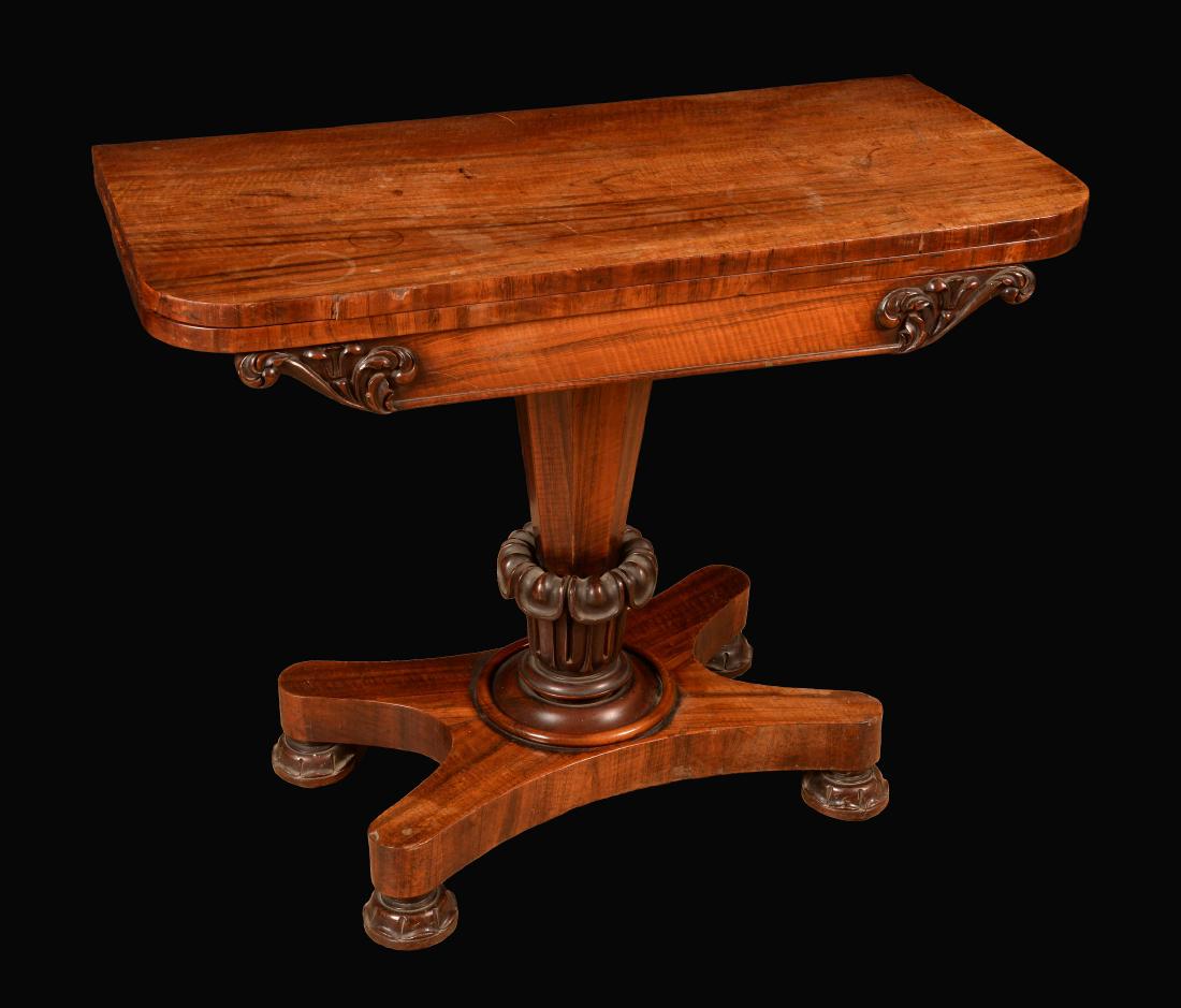 A William IV rosewood rounded rectangular card table,: A William IV rosewood rounded rectangular card table, folding top enclosing a baize lined playing surface above a deep frieze carved with scrolling acanthus and lotus, tapered octagonal pillar, bold l