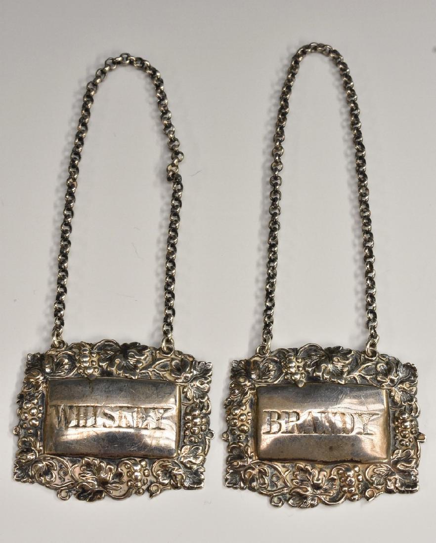 A pair of Victorian silver shaped rectangular wine: A pair of Victorian silver shaped rectangular wine labels, Brandy and Whiskey, the borders embossed with fruiting vine, 4.5cm wide, Colin Hewer Cheshire, Birmingham 1888