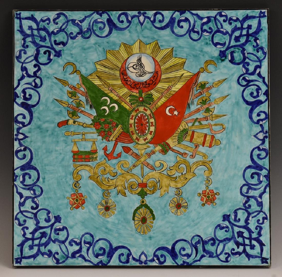 A large Turkish tile, brightly decorated with the coat: A large Turkish tile, brightly decorated with the coat of arms of the Ottoman Empire, on a turquoise ground, 40cm square