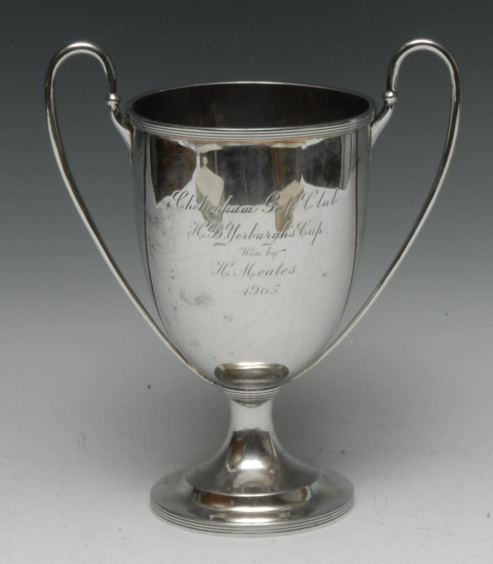 An Edwardian silver urnular pedestal trophy cup, scroll: An Edwardian silver urnular pedestal trophy cup, scroll handles, domed circular foot, reeded borders, 23.5cm high, Charles Stuart Harris, London 1905, 17.5oz