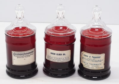(3) Glass ruby red apothecary jars with lids