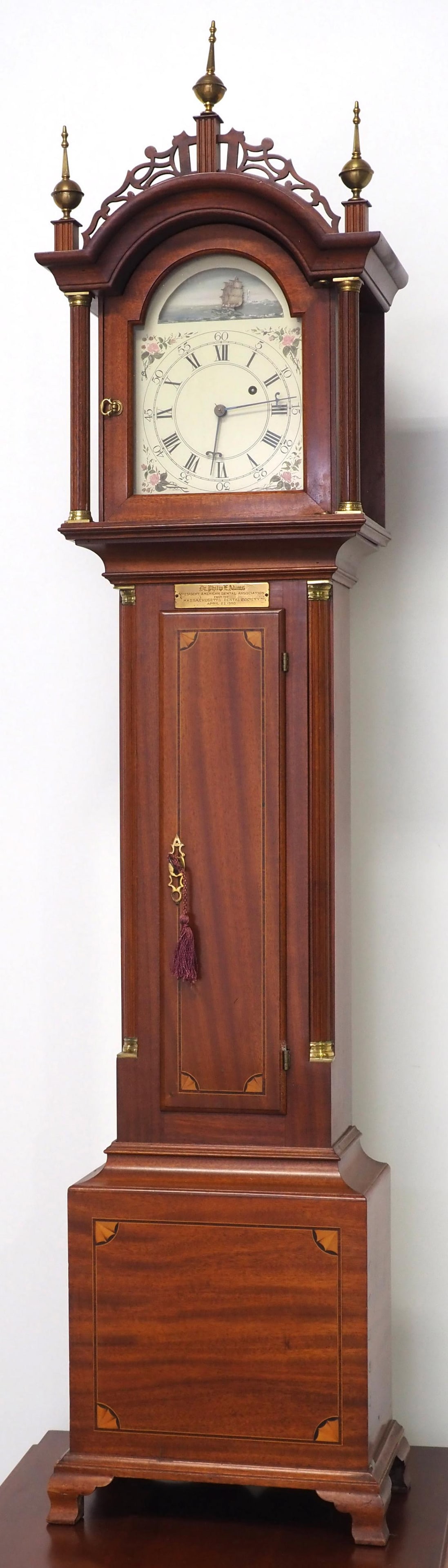 Elmer O. Stennes Dwarf Grandfather Clock: Elmer O. Stennes Dwarf Grandfather Clock with Painted Tin Dial, Animated Rocking Ship Arch Movement, Inlaid Mahogany Case with Brass Finials and Accents, Brass Tag for Dr. Philip E. Adams, President A