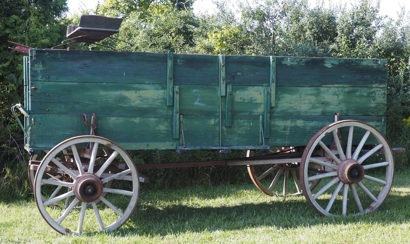 Green triple-board box wagon: Green triple-board box wagon with seat and pole, rear wheels 40"dia, front wheels 36"dia, overall 149"L - Fair * * NOT ELIGIBLE FOR IN-HOUSE SHIPPING. Please contact the auction house for transport