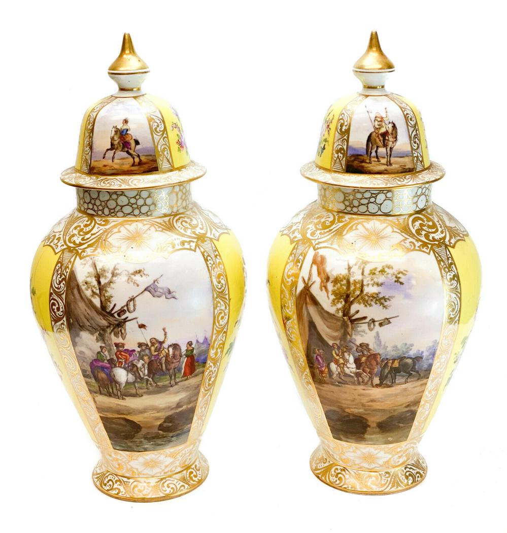 Pair Dresden Augustus Rex Porcelain Urns: A pair Dresden Augustus Rex hand painted porcelain lidded urns, circa 1900. A yellow ground with hand painted hunting scenes to the central areas. Hand painted flowers to the yellow ground. Augustus R