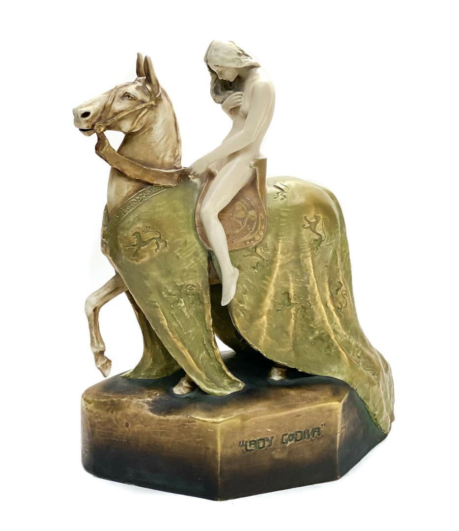 Amphora Porcelain Sculpture- Lady Godiva: Amphora Austria porcelain pottery sculpture- Lady Godiva by W. Lachner, 1907. The sculpture depicts a nude beauty riding on a draped horse adorned with a rampant lion armorial. Artist signed "W. Lachn