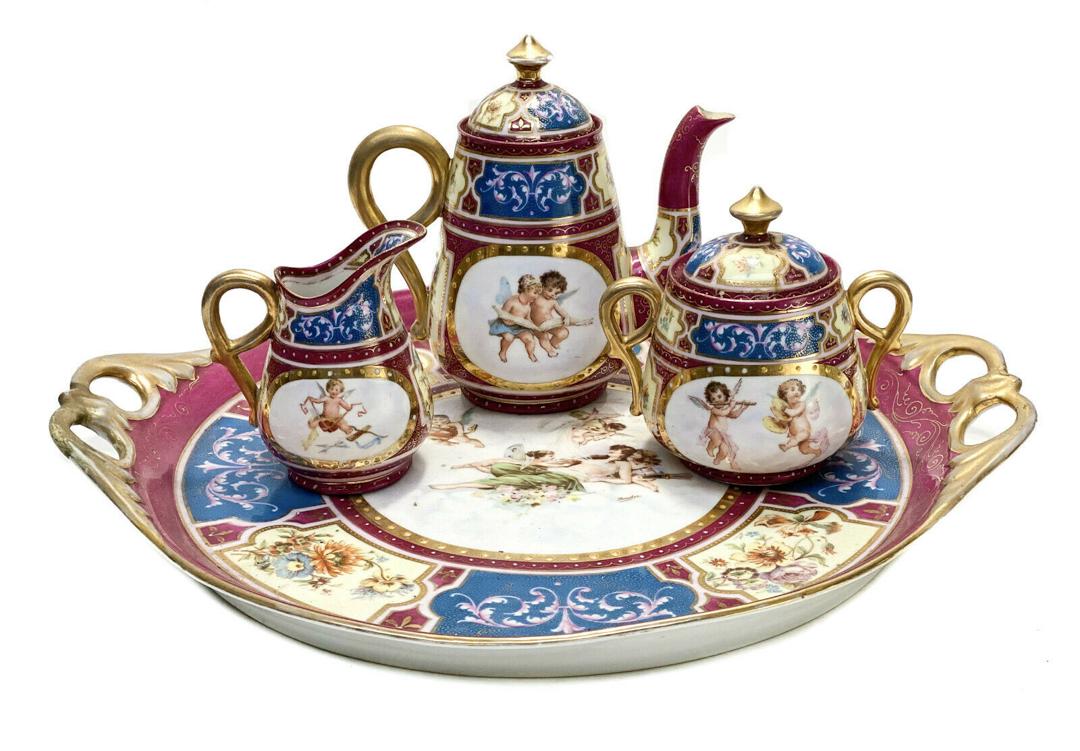 Royal Vienna Austria Partial Tea Service. Cracked: Royal Vienna Austria tea service. A wine red, white, and blue ground with hand painted cherubs to the central areas and gilt to the handles. Royal Vienna mark to the underside base, though most are co