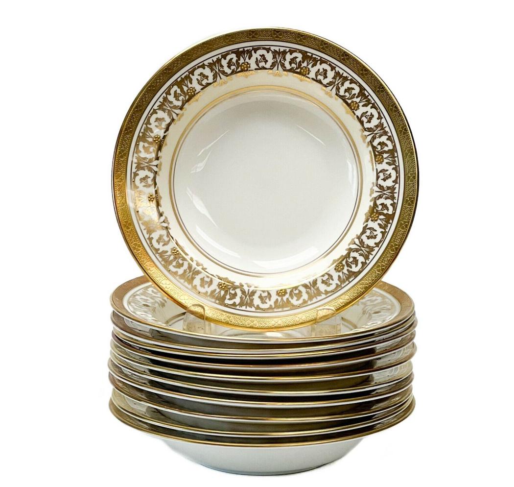 11 Aynsley England Porcelain Rimmed Soup Bowls in Kenilworth Ivory Raised Gold: 11 Aynsley England porcelain rimmed soup bowls in Kenilworth Ivory, circa 1940. A white center with an off-white ground to the edge with ornate gilt foliate decoration with raised gold floral accents.