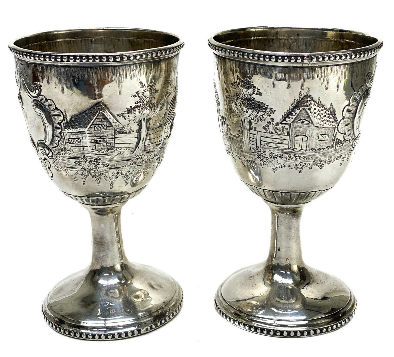 Pair American Coin Silver Repousse Wine Goblets: Pair American coin silver repousse wine chalices or goblets, circa 1860. Repousse landscape scenes to the central areas. Beaded accents to the top and base rim. Both with heavily worn 3 letter monogra