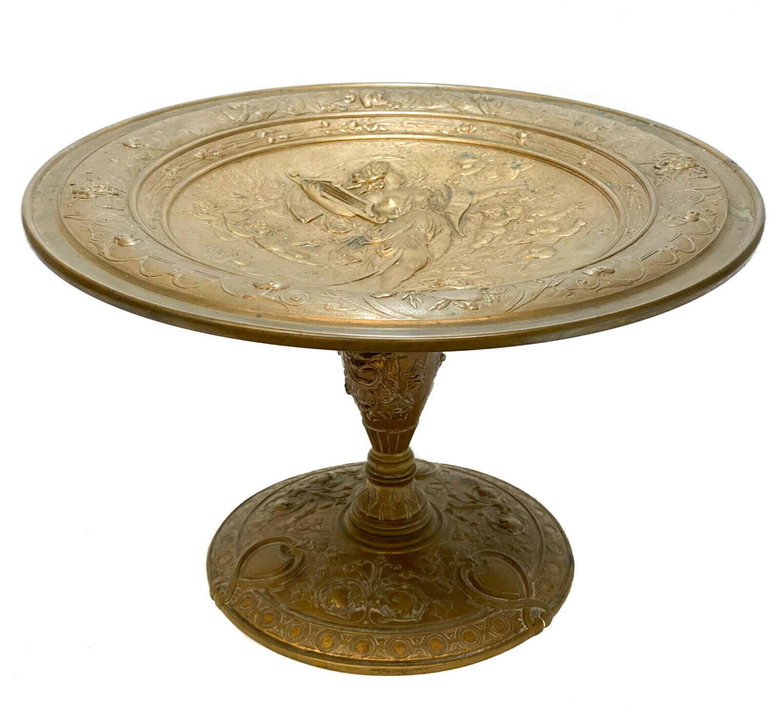 French Patinated Bronze Footed Tazza, circa 1900: French patinated bronze footed tazza, circa 1900. The central area depicts an ornate repousse beauty playing an instrument with cherubs surrounding her. Vine leaves and heart accents to around the edg