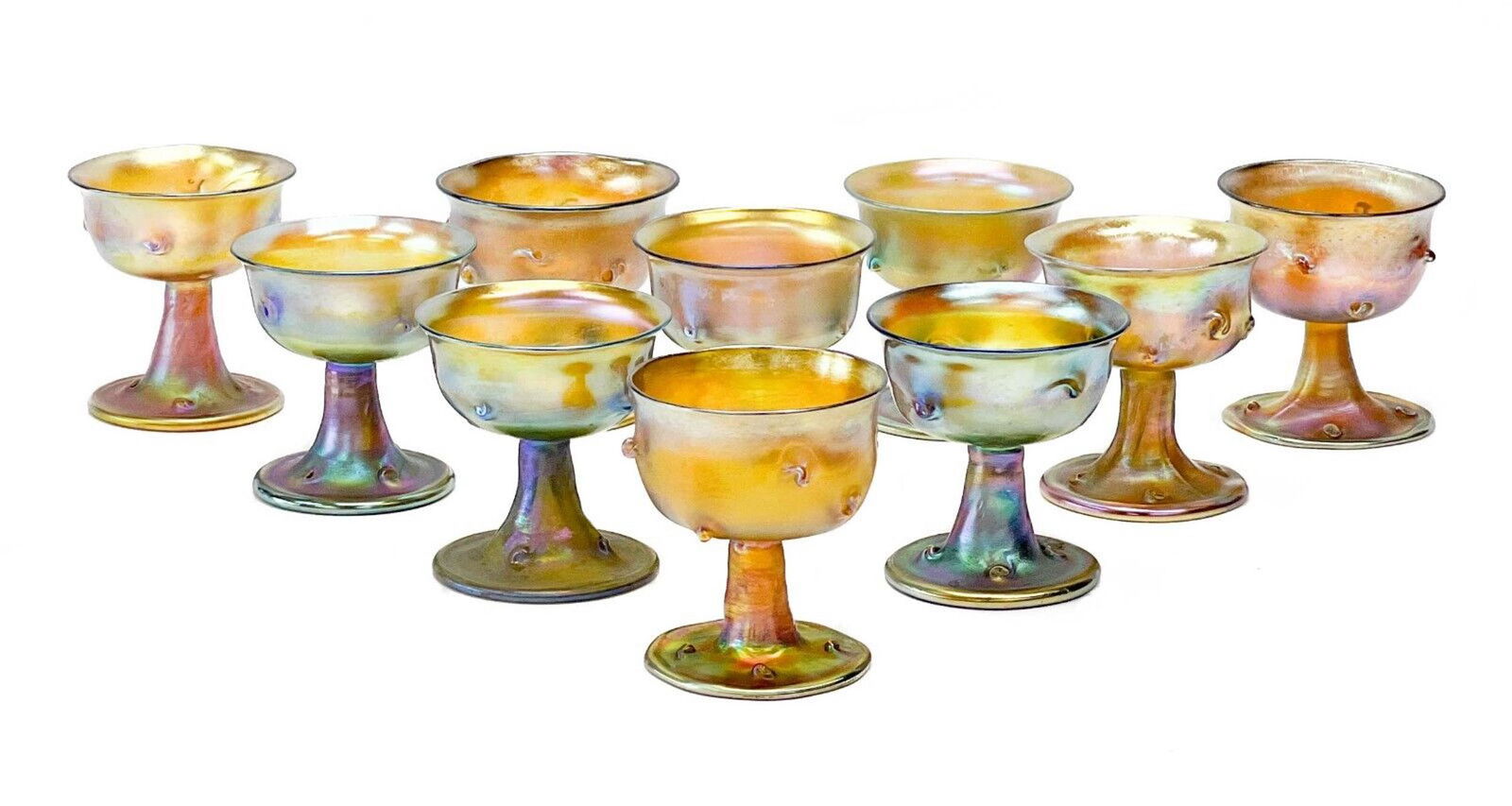 10 Tiffany Favrile Iridescent Wine Goblets: 10 Louis Comfort Tiffany LCT favrile glass wine goblets. Various hued iridescence with molten prunts or "pigtails" to the exterior of the bowl. LCT Tiffany marks to the underside, circa 1900. With var