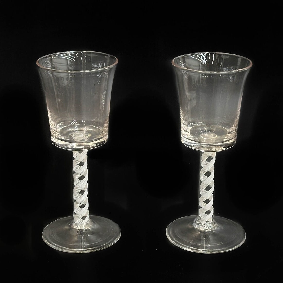 Pair English Air Twist Glass Wine Glasses 18th century: Pair English Air Twist Glasses, likely 18th century with a rough pontil and pronounced striations. White air twist decoration to the stem. Weight: Approx. .5 lb Measurements: Approx. 3 inches diameter