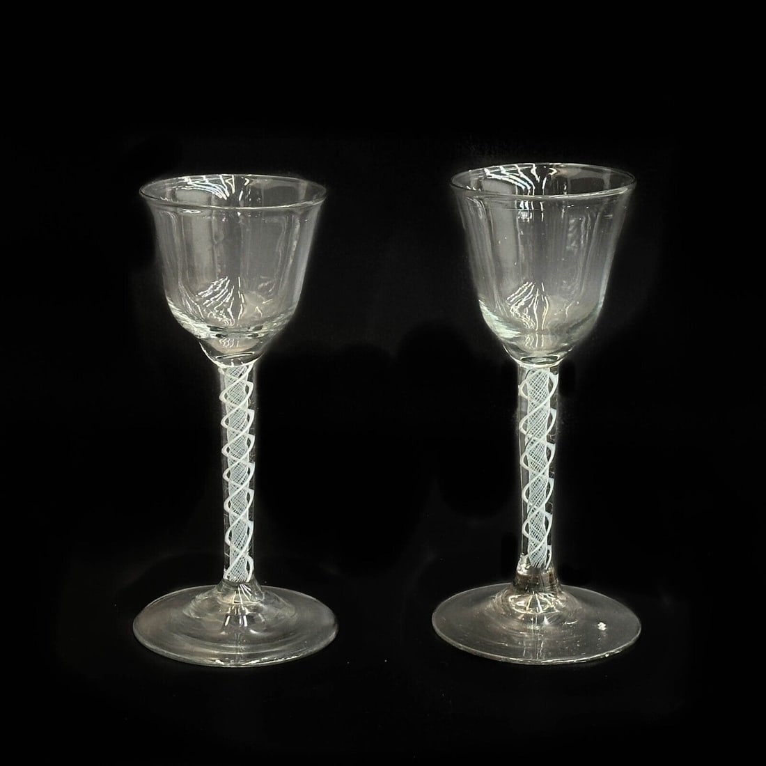 Pair English Air Twist Glass Wine Glasses 18th century: Pair English Air Twist Glasses, likely 18th century with a rough pontil and pronounced striations. White air twist decoration to the stem. Weight: Approx. .5 lb Measurements: Approx. 3 inches diameter