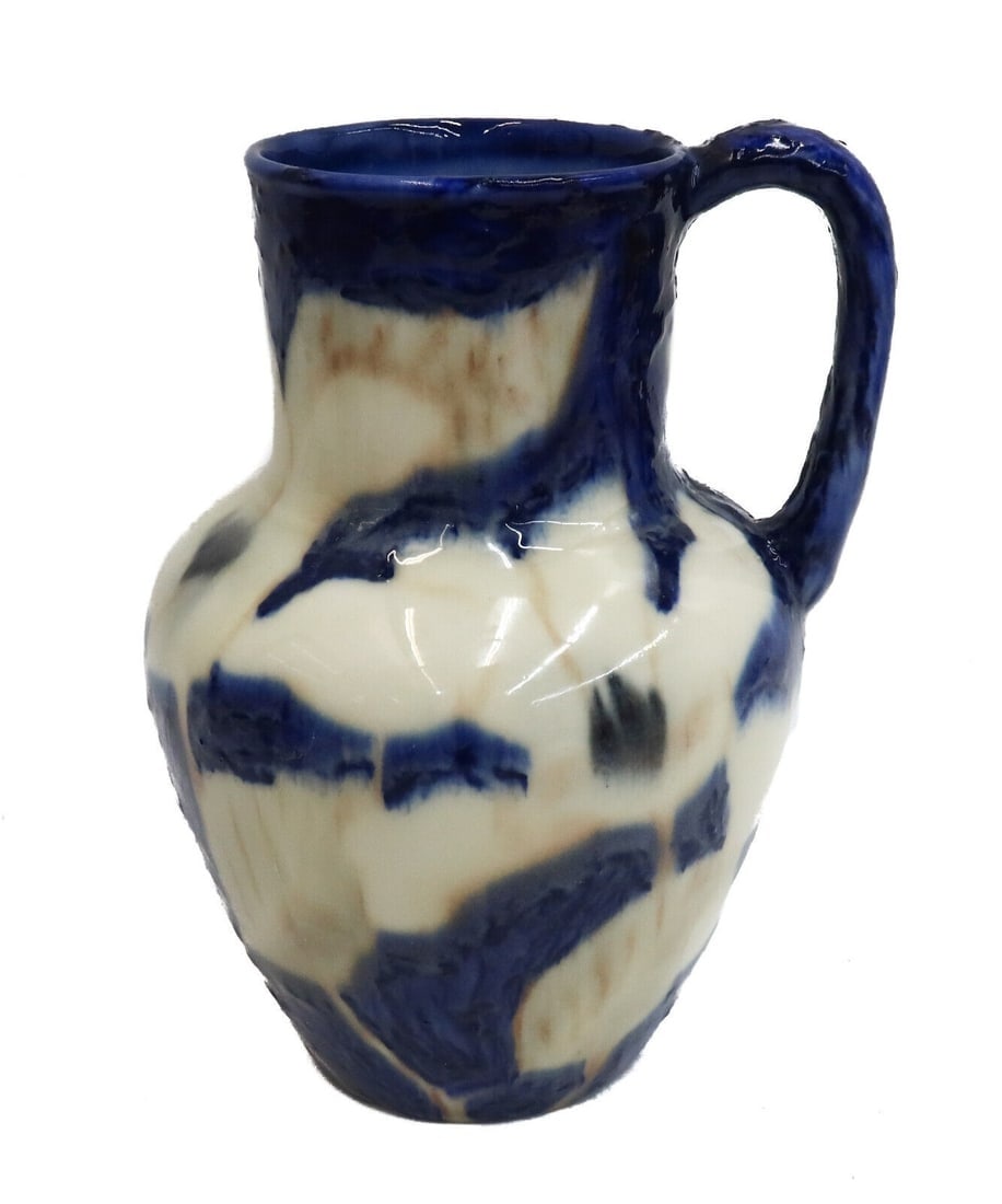 Rookwood Glazed Pottery Handled Pitcher Jug by Jens Jensen #6320 1943: Rookwood glazed pottery handled pitcher jug by Jens Jensen #6320, 1943. A pale yellow ground with raised blue decoration throughout. Rookwood mark to underside dating to 1943 and initials for Jens Jen