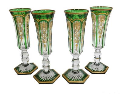 4 Baccarat France Emerald Green to Clear and Gilt Champagne Flutes in Empire: 4 Baccarat France champagne flute goblets in Empire. Emerald green to clear with gilt foliate designs to panels. Starburst cut base. Unmarked, but work of Baccarat. Weight: Approx. 3 lbs
