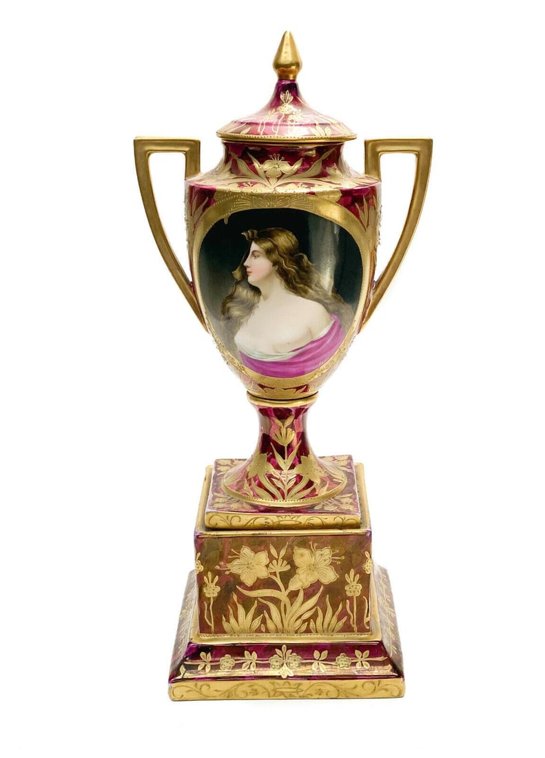 Royal Vienna Hand Painted Porcelain Double Handled Urn: Royal Vienna Austria hand painted porcelain double handled urn, circa 1900. A burgundy red ground wit gilt leaves and floral accents throughout. The central area depicts a hand painted partially nude